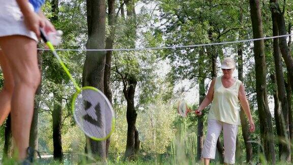 活跃的老年人在树丛中打羽毛球