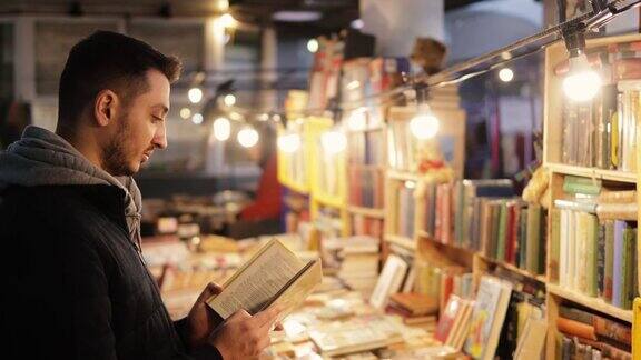 一个年轻人在二手书店里看旧书在波多贝罗路跳蚤市场的一个市场摊位上出售的旧书