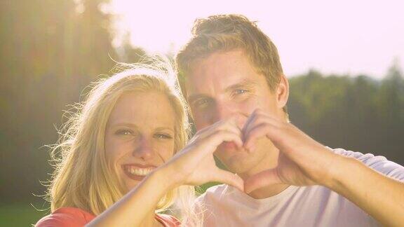 肖像:一对可爱的夫妇在户外约会时用手指做一个心形