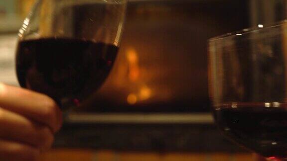 一对夫妇在燃烧的壁炉旁碰杯喝红酒
