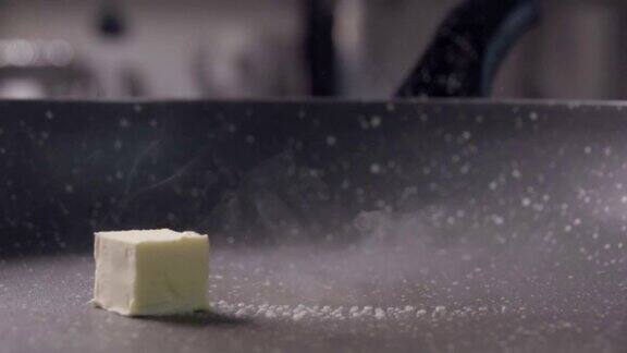 将一块黄油块滑到煎锅上融化慢动作