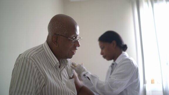 女医生给一个年长的病人注射疫苗