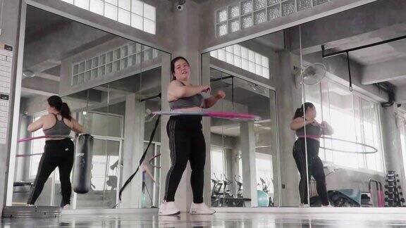 (慢镜头)超重女子在健身房里玩呼啦圈