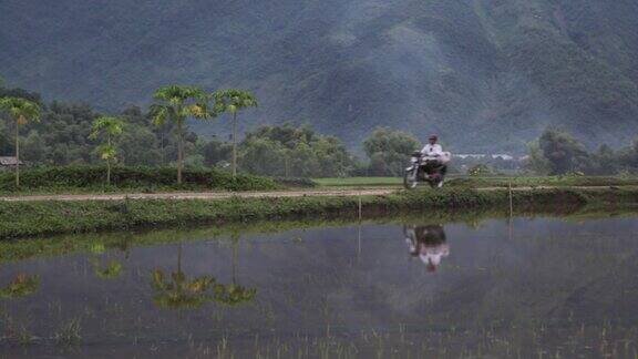 一名男子驾驶摩托车穿过风景优美的越南沙巴麦洲田野