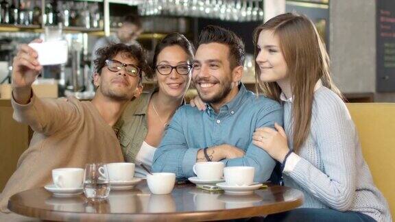 一群年轻的混血儿微笑着在咖啡店用手机自拍