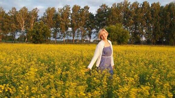 年轻美丽的白种人金发女郎走在一片黄色的花