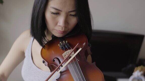 一名亚洲女子在隔离期间在家拉小提琴