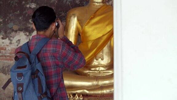 英俊的年轻亚洲男子游客的肖像旅行和使用胶卷相机在泰国寺庙拍照亚洲男子博客愉快享受休闲生活方式旅游