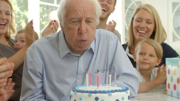 爷爷在生日蛋糕上吹蜡烛慢镜头