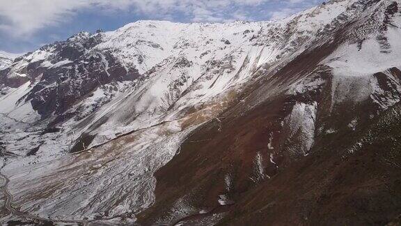空中镜头-环绕安第斯山脉山谷飞行令人惊叹的景色在一个阴天的冬天白雪覆盖安第斯山脉的一个令人敬畏的崎岖景观与圣何塞火山在远处