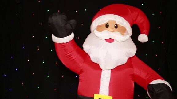 一个真人大小的充气圣诞老人娃娃穿着红色的衣服快乐地摇晃着挥手问候