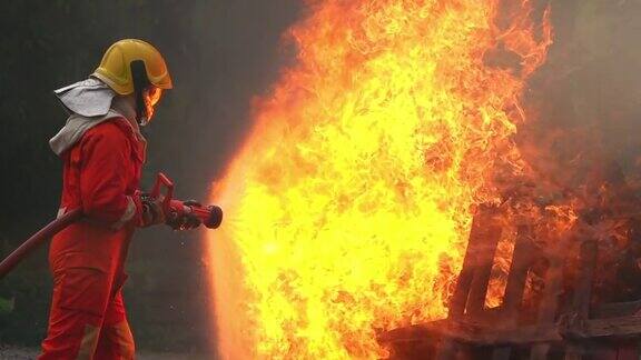 身着消防服执行安全救援任务的消防队员用灭火器从消防软管中喷出的噼啪火焰在燃烧的房屋内扑灭消防员正在救火