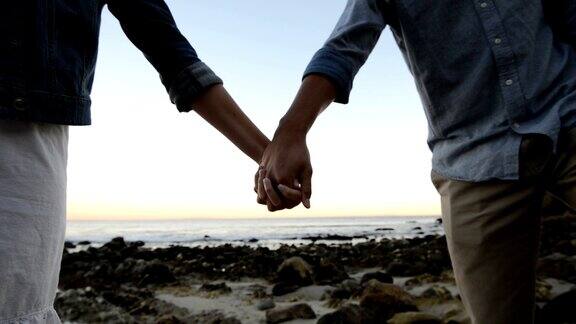 在海滩上牵着手的多民族浪漫情侣