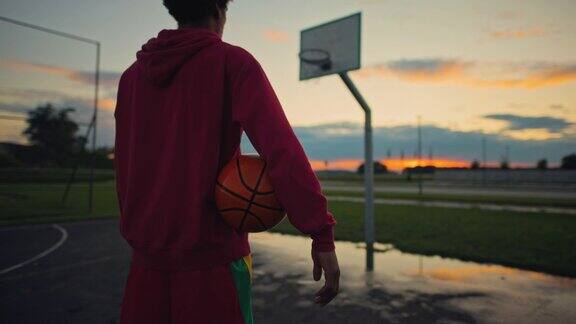 篮球运动员站在篮球场上看夕阳