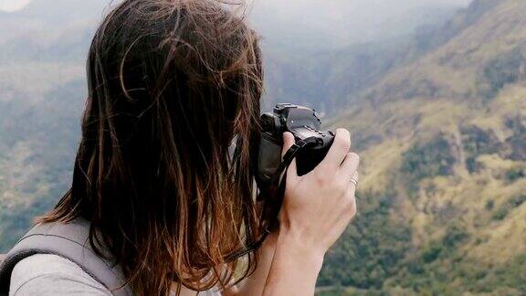 特写快乐的年轻记者女人与背包和飞行的头发拍摄史诗山脉风景在斯里兰卡的照片