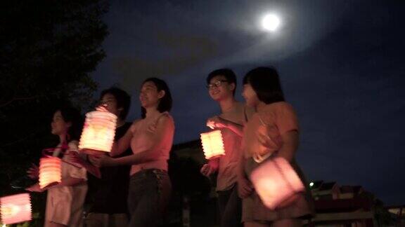 亚洲华人妈妈带着孩子和侄子拿着纸灯笼庆祝中秋节