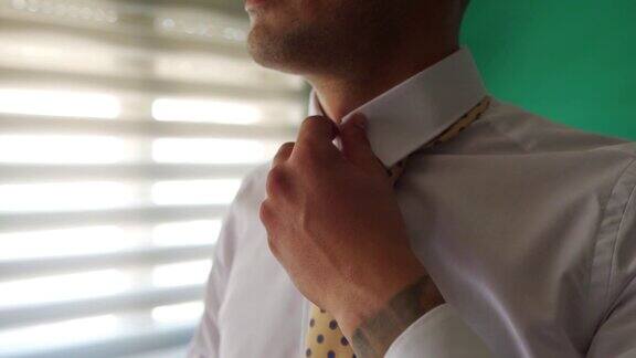 新郎在为他的婚礼打扮自己时正在调整他优雅的领带