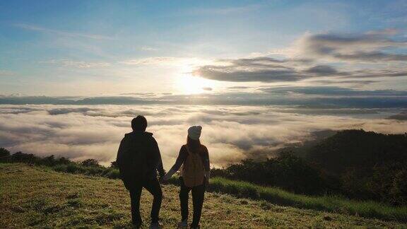 年轻的情侣旅行者在早晨看日出和山上的雾海旅游的生活方式概念