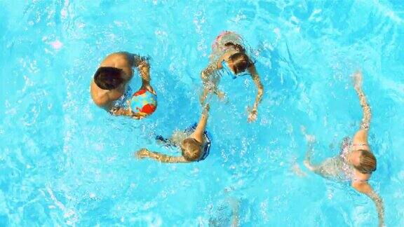 一个阳光明媚的日子一个年轻的家庭在游泳池里打球