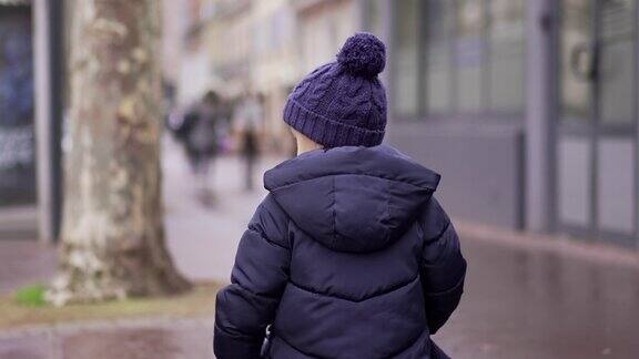 蹒跚学步的婴儿在冬天的人行道上奔跑婴儿在城市里奔跑