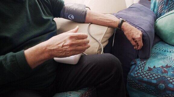 一位老人在家里的沙发上测量自己的血压