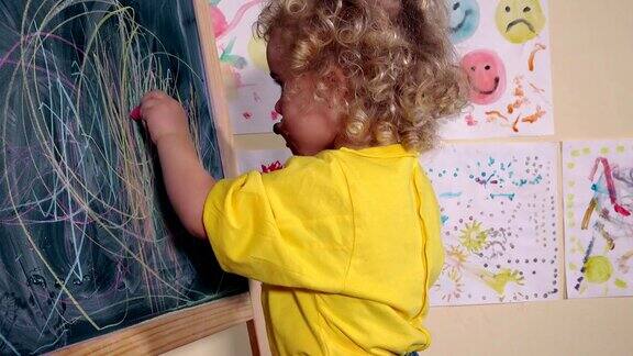 孩子用两支粉笔在黑板上画画