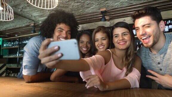 一群开心的朋友在酒吧用智能手机自拍