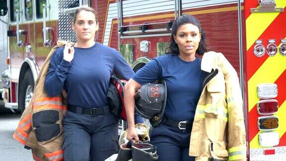 两个女消防员走在消防车旁边