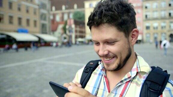 一个留着胡子的年轻人在户外用手机拍照