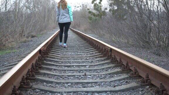 这个女孩乘火车去一个孤独的女孩沿着铁轨走着