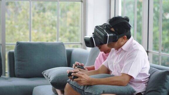 亚裔父亲和他的女儿一起在家里的客厅里玩电子游戏
