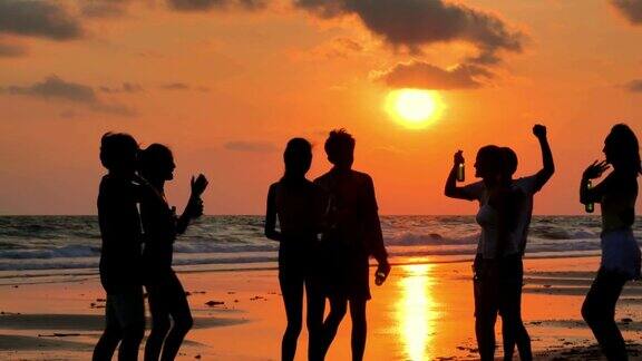 一群朋友在海滩上玩和喝酒的剪影假期iStock