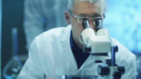 科学家通过显微镜观察并在平板上书写数据