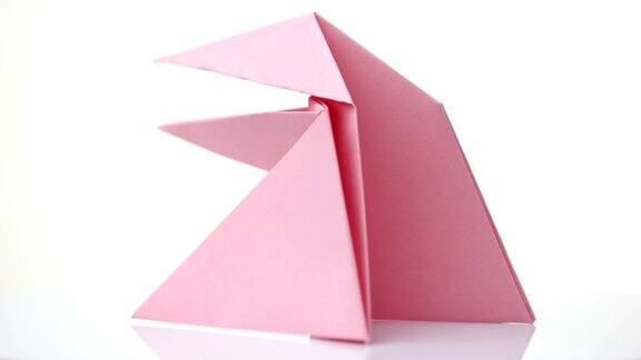 粉红色的折纸青蛙被隔离在白色上