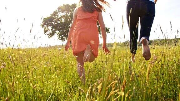 快乐的女人和女孩赤脚在草地上奔跑