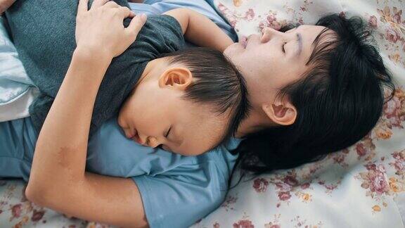 小男孩在卧室里睡在妈妈的胸口上