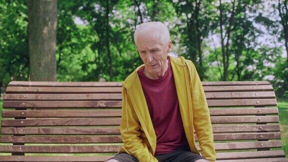 精疲力竭的老人在慢跑后坐在公园长椅上喘口气