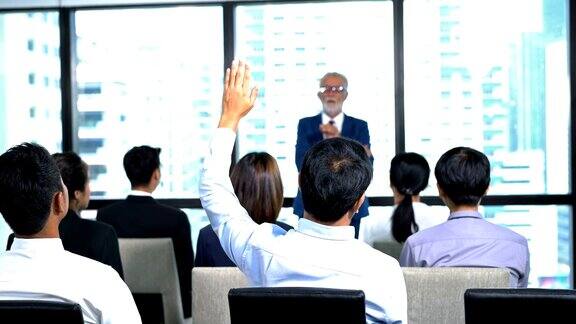 在会议活动中在会议厅举手提问的男发言人讲座期间观众举手