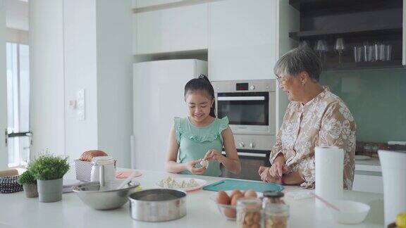 亚洲的中国年轻女孩在周末的闲暇时间在厨房学习她的祖母准备中国饺子