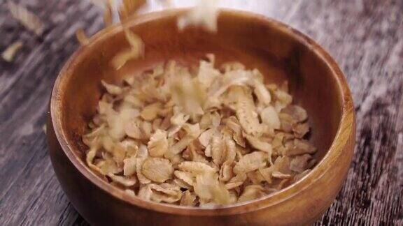 未煮熟的干谷物和小麦片落入粗糙的木制乡村碗中