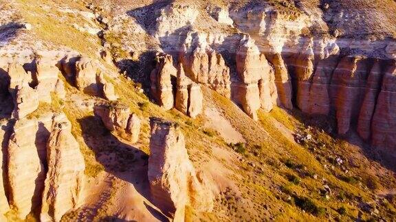 巨大壮观的岩石壮观的无人机在日落时飞过色彩斑斓的山谷红色和粉红色的山丘岩石沙漠中戏剧性的地质奇观鸟瞰美丽的4k风景