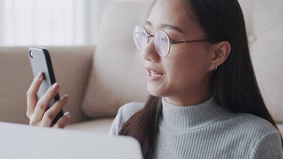 一个美丽的亚洲女人使用电话的肖像亚洲女孩通过视频电话与朋友聊天在她的家的客厅里