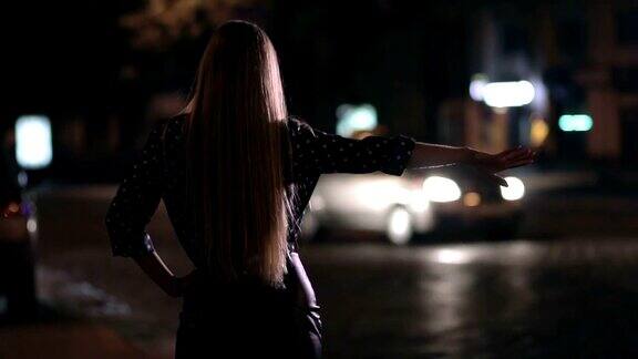 迷人的女孩晚上在街道上搭便车