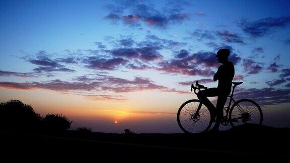 日落时岩石上骑自行车的人的剪影