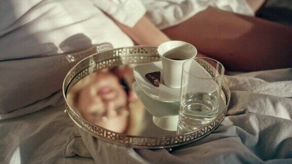 女人使用智能手机早上在床上喝咖啡