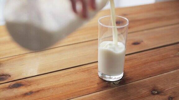 用手把牛奶倒进木桌上的玻璃杯里