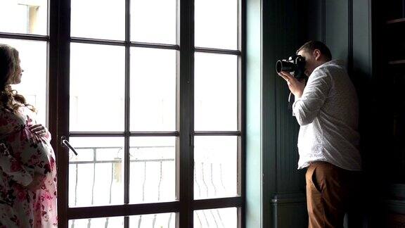 专业摄影师在窗户附近拍摄孕妇模特