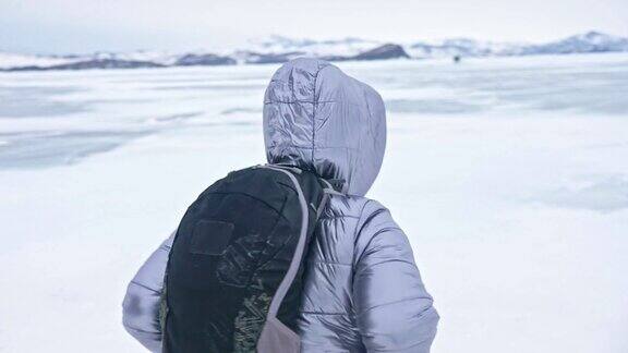 女人在贝加尔湖冰面上的旅行冬岛之旅女孩在冰岩石下行走游客看着美丽的冰洞极限跋涉和步行背包客在大自然中休憩