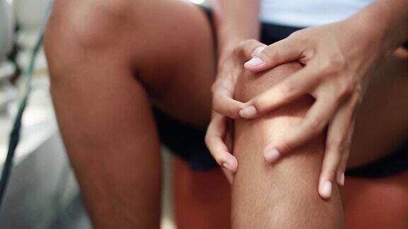 年轻女人按摩她疼痛的膝盖年轻女人膝盖疼痛保健理念