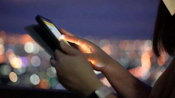 女人的手在晚上用手机用圆圈灯散焦